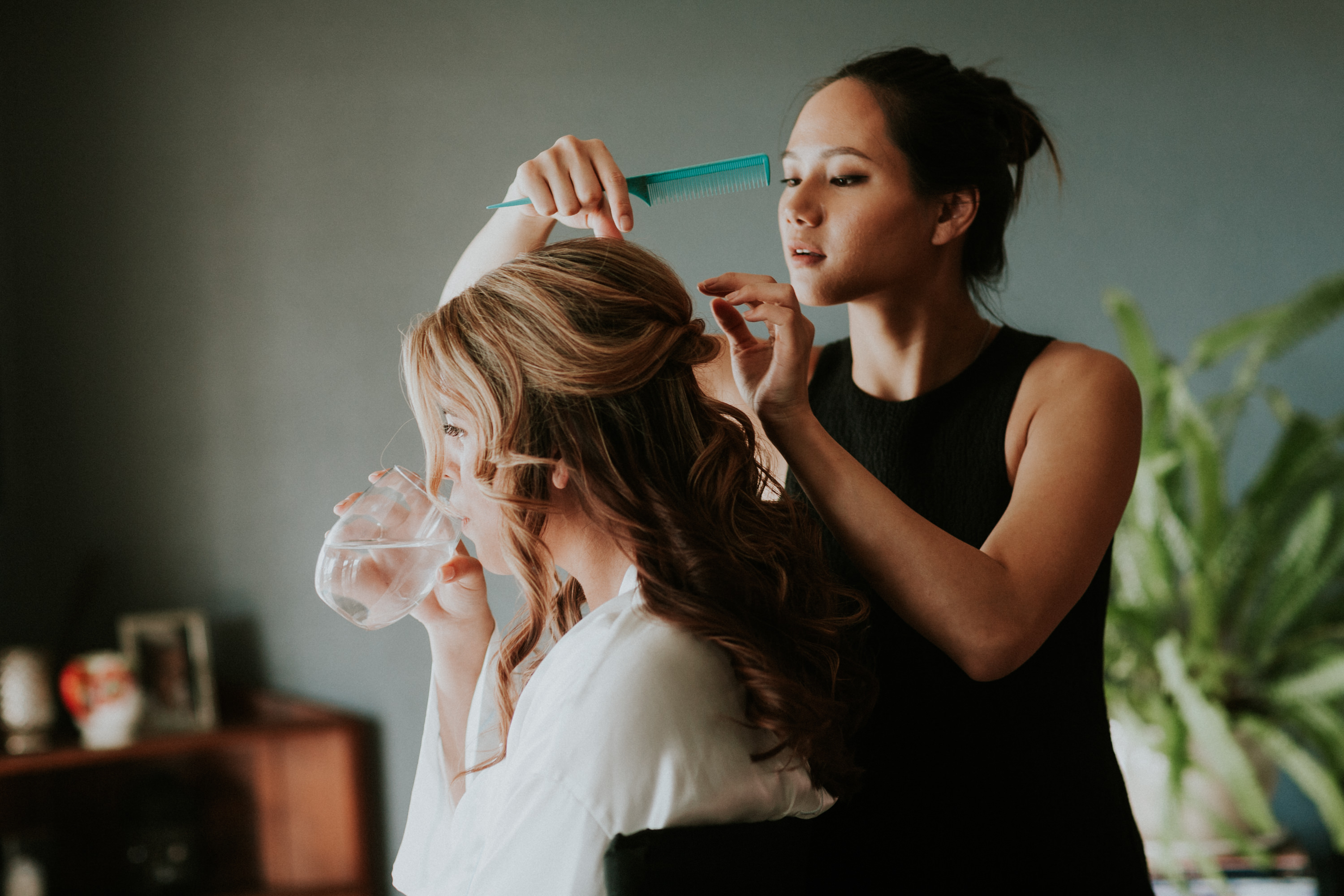 bride getting hair done, bride drinking water while getting hair done