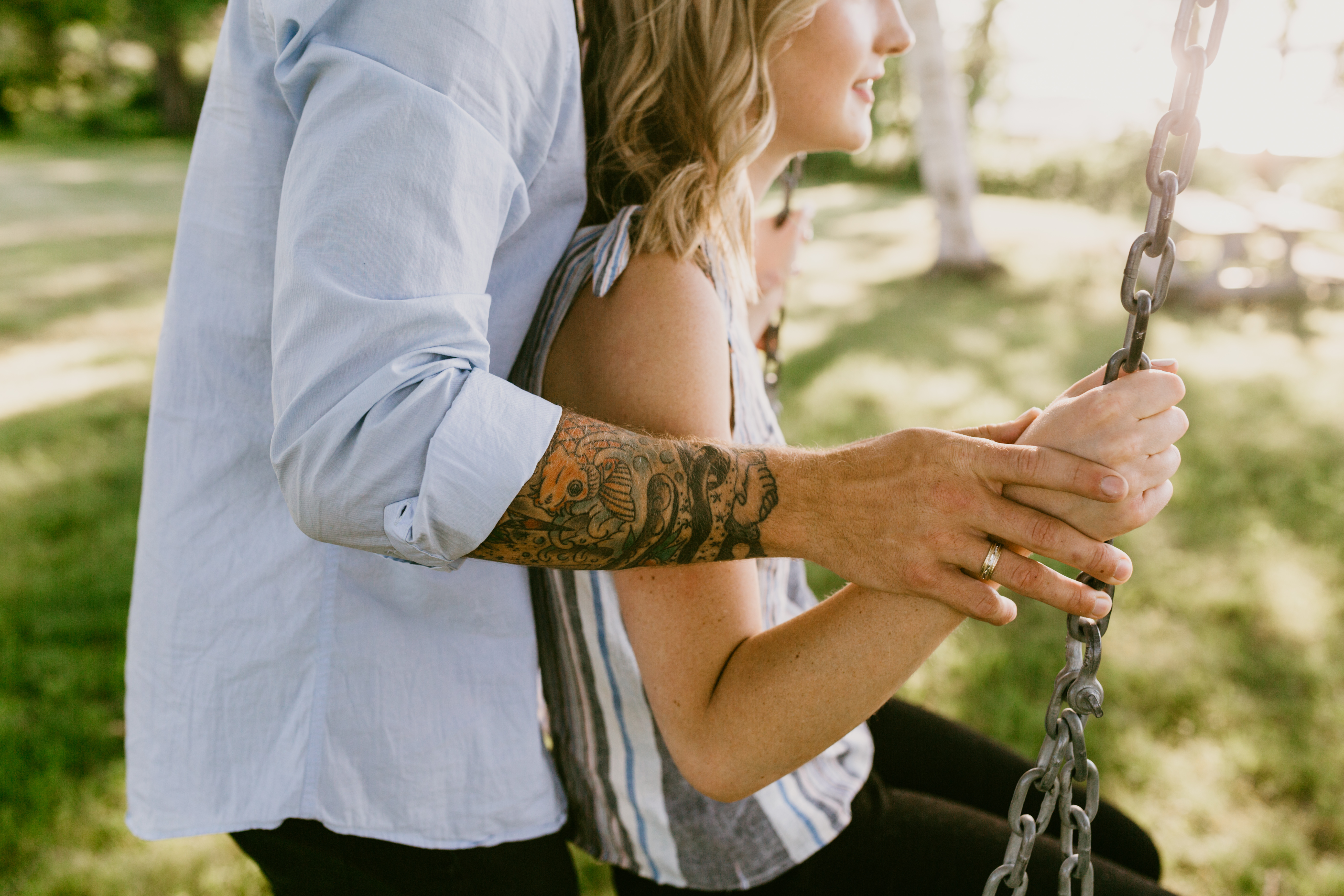 guy with tatto pushing fiance on swing