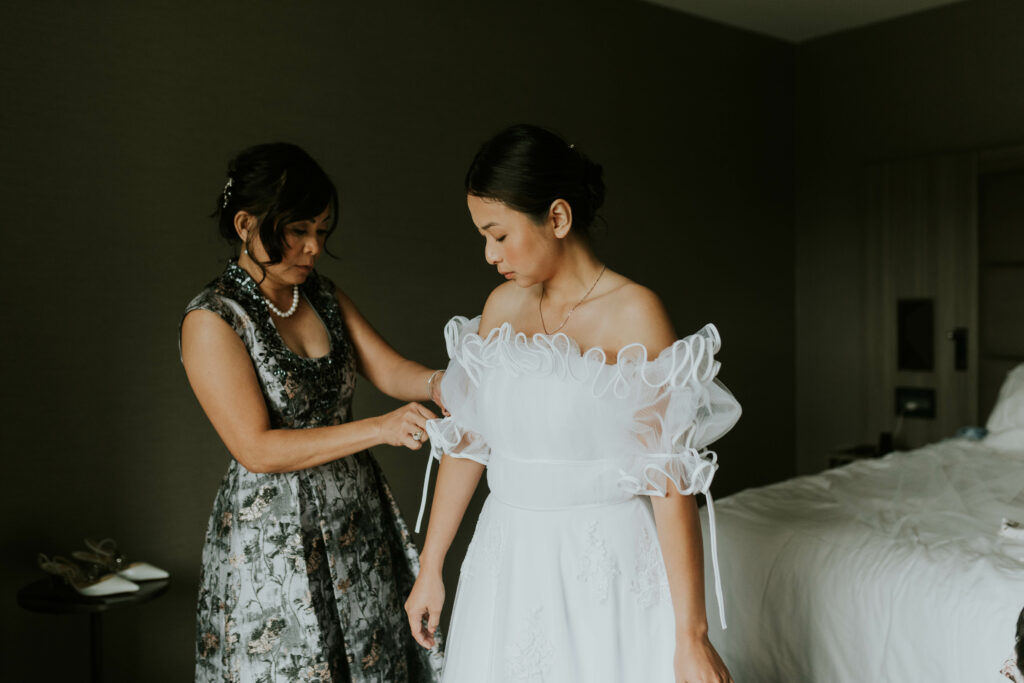 mother of the bride doing up wedding dress