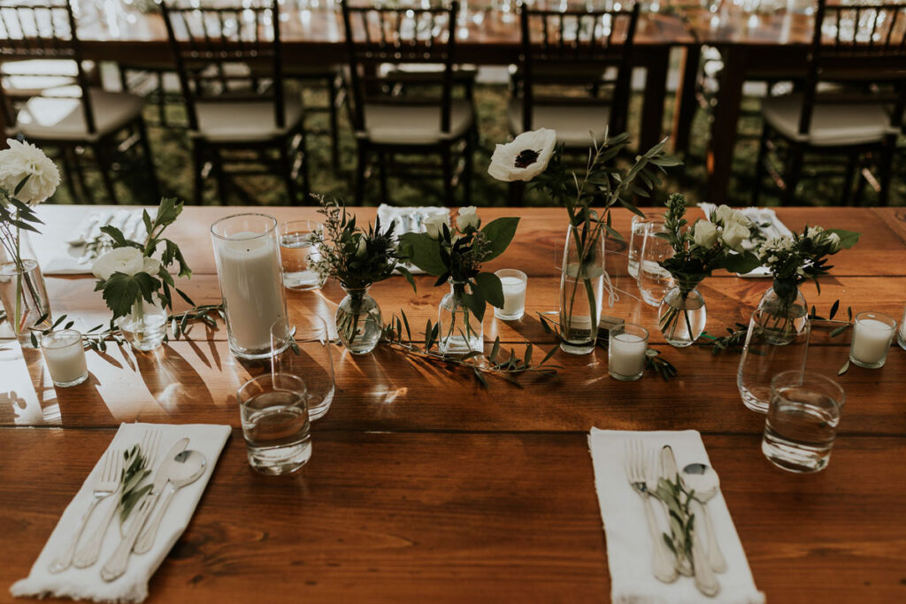 white flowers in small vases on a long wooden table at a Cape Cod wedding reception