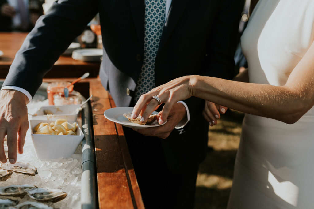 shot of a bride's hand holding a plate with an empty oyster on the half shell
