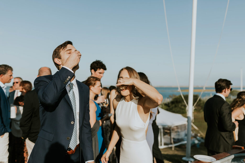 bride and groom slurp oysters during their outdoor wedding reception on Cape Cod
