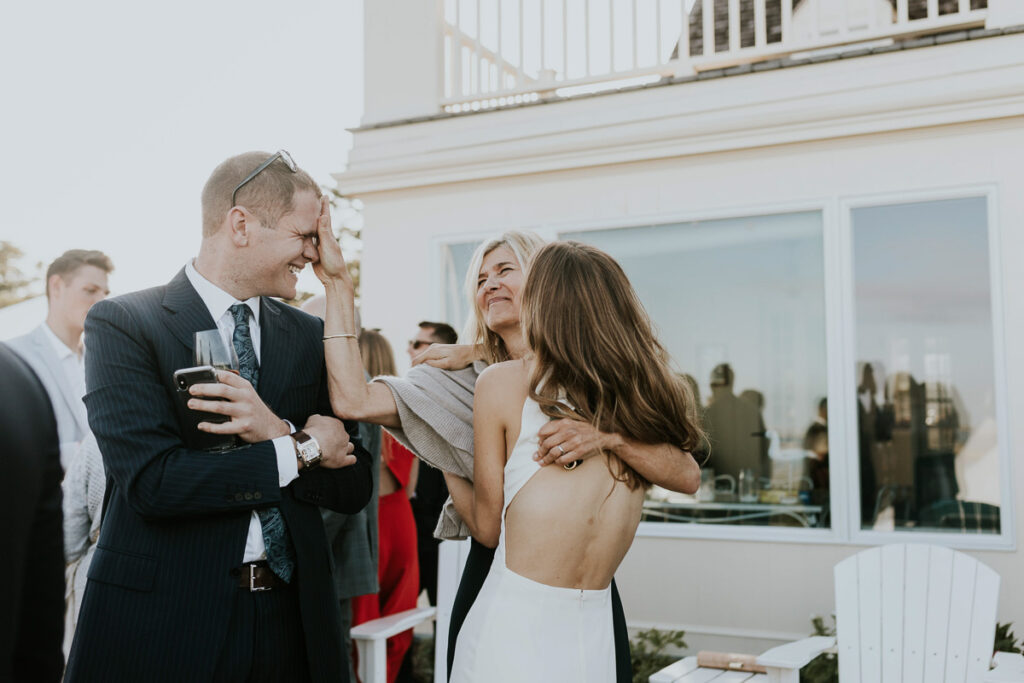 Bride hugs her mother and smiles with her brother after wedding ceremony on Cape Cod