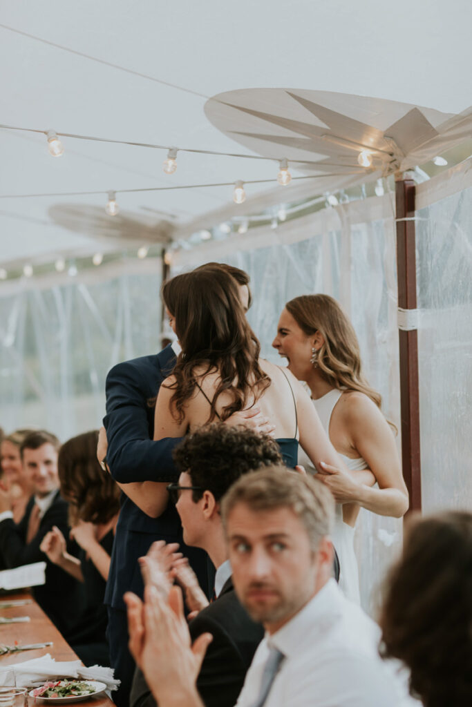 group hug between bride, groom, and bridesmaid at their Cape Cod wedding reception