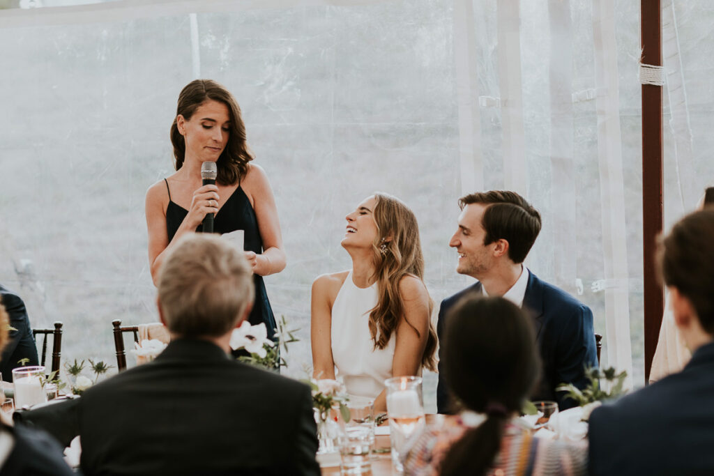 bride laughs hysterically at Maid of Honour's speech during Cape Cod wedding reception