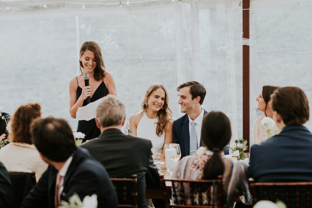 Maid of Honour delivers speech to bride and groom in their Cape Cod wedding reception tent