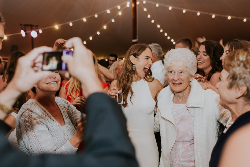 Cape Cod bride laughs with friends as she hugs her grandma on the dancefloor during the reception