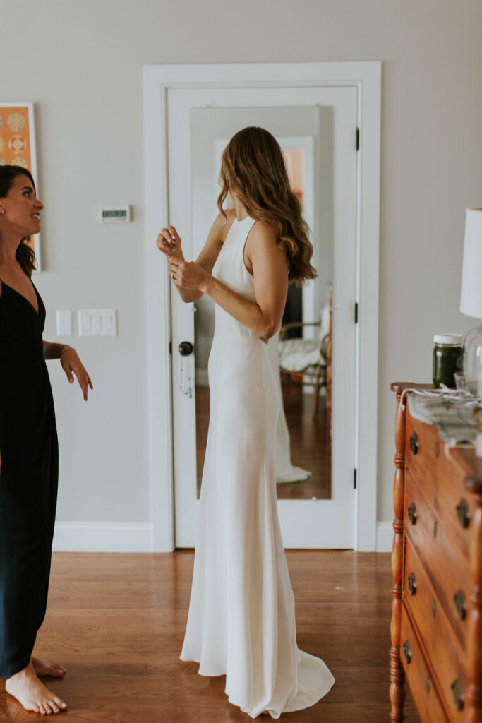 bride looks at the back of her dress in the mirror