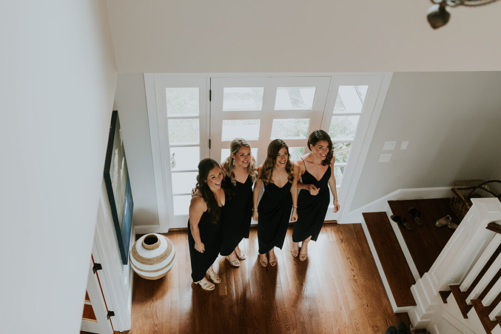 bridesmaids wait for bride to come down the stairs after getting ready