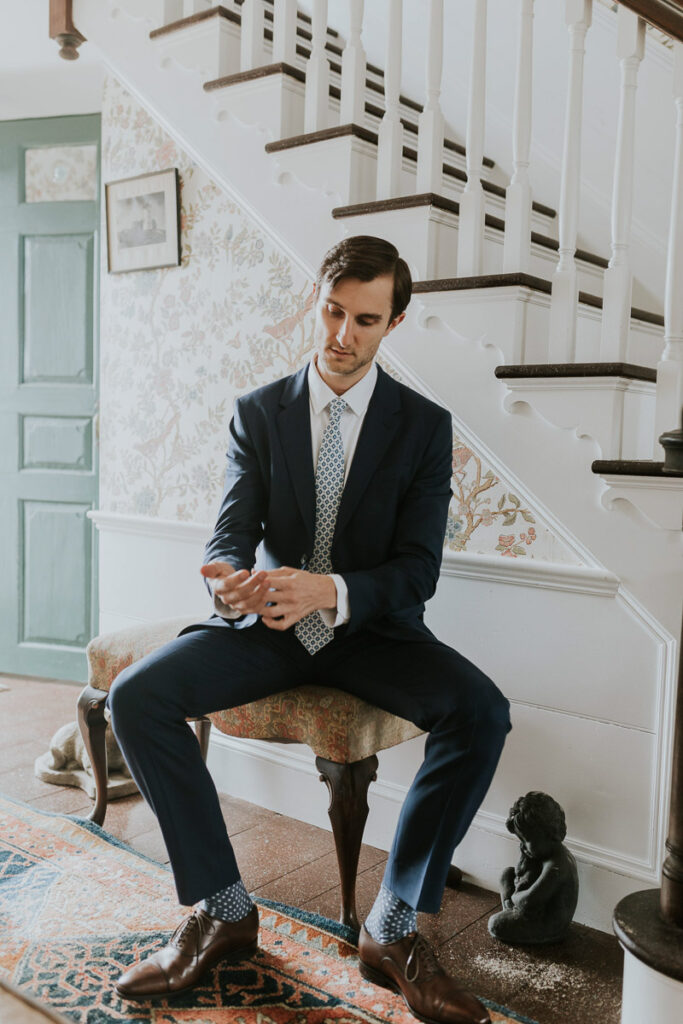 Groom adjusts cuffs and shows off polka dot socks as he prepares for upcoming wedding ceremony