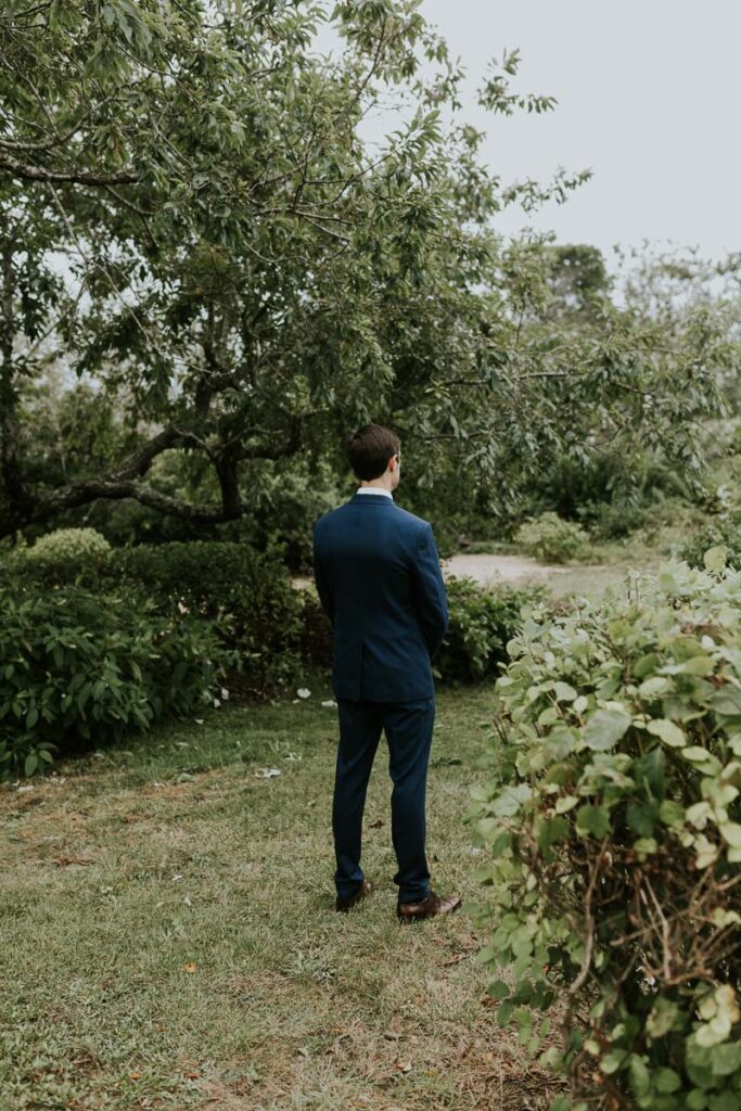 groom stands and patiently waits for his bride to approach him during first look
