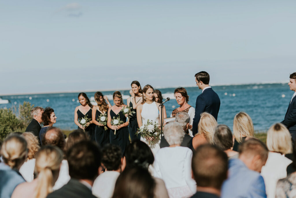 shot of bridal party and ocean in background during wedding ceremony on Cape Cod