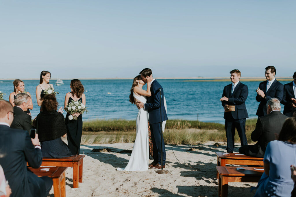bride and groom share their first kiss at the end of their marriage ceremony on the beach in Cape Cod